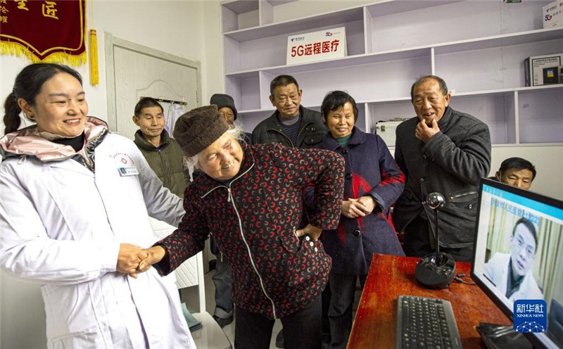 安徽省金寨縣大灣村村民方臨芳（前左二）指著自己身體疼痛的部位，在村醫(yī)袁玲（左一）的幫助下向5G遠(yuǎn)程醫(yī)療會(huì)診的專家講述病情（2020年12月3日攝）。新華社發(fā)（陳力 攝）