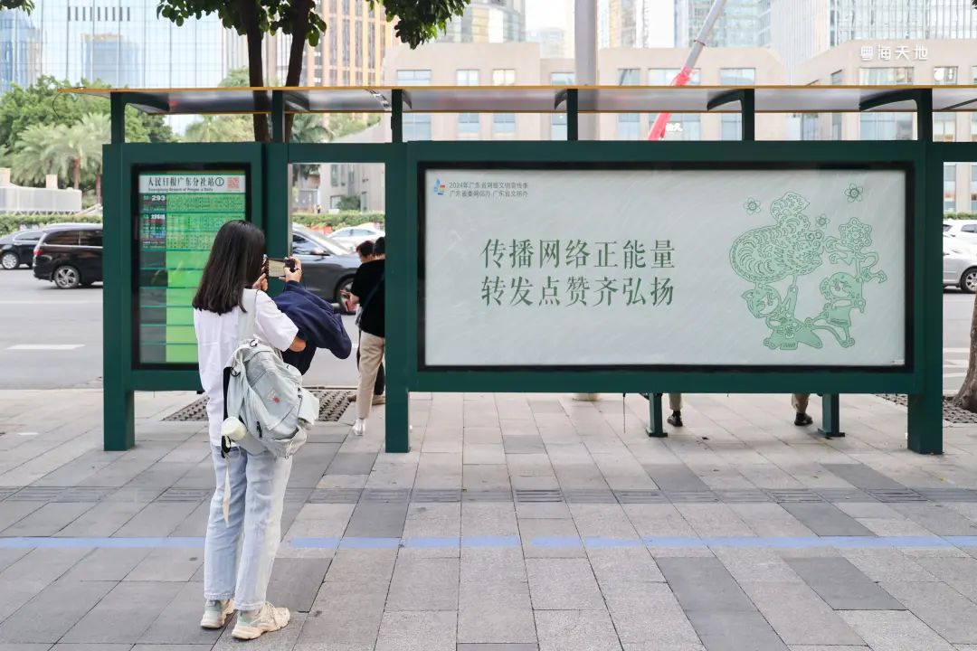 在人民日報廣東分社公交站，市民駐足拍攝廣東網(wǎng)絡文明海報。