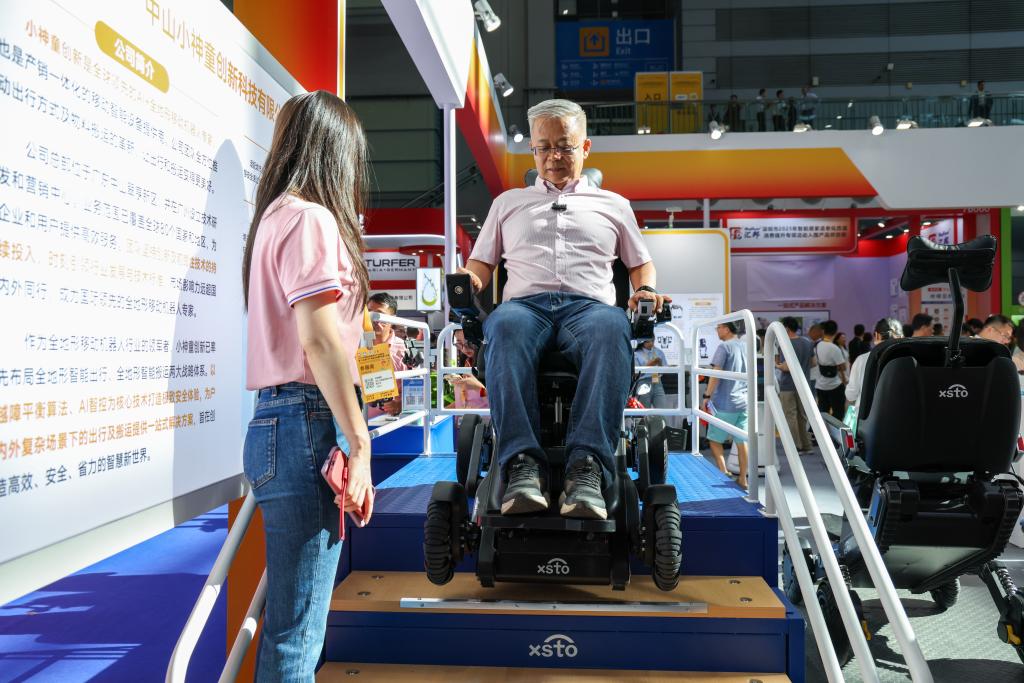2025年9月12日，在2025深圳國(guó)際智慧養(yǎng)老產(chǎn)業(yè)博覽會(huì)上，觀眾在展會(huì)現(xiàn)場(chǎng)體驗(yàn)一款可以上下樓梯的智能出行機(jī)器人。新華社記者 梁旭 攝